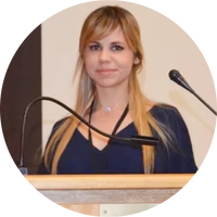 A person speaking at a podium with microphones.